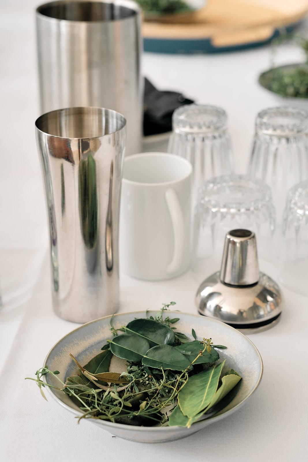 A cocktail shaker and fresh herbs laid out on the mocktail-making table