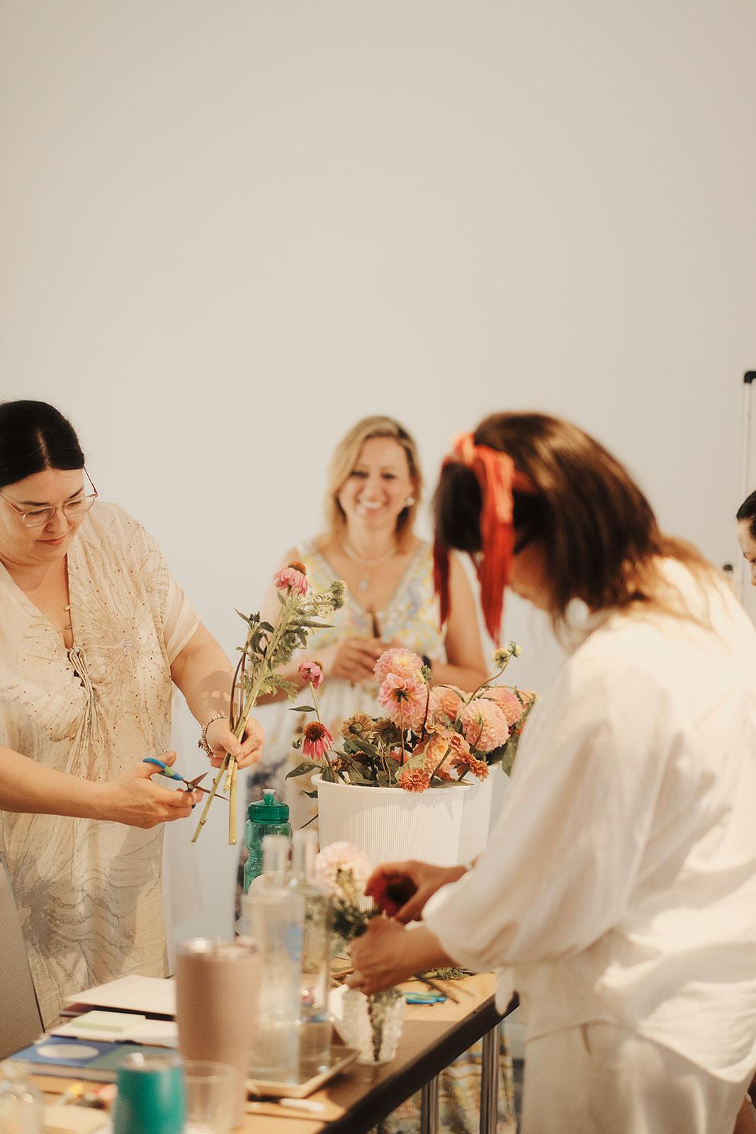 Two women arranging flowers together at a candlelit table