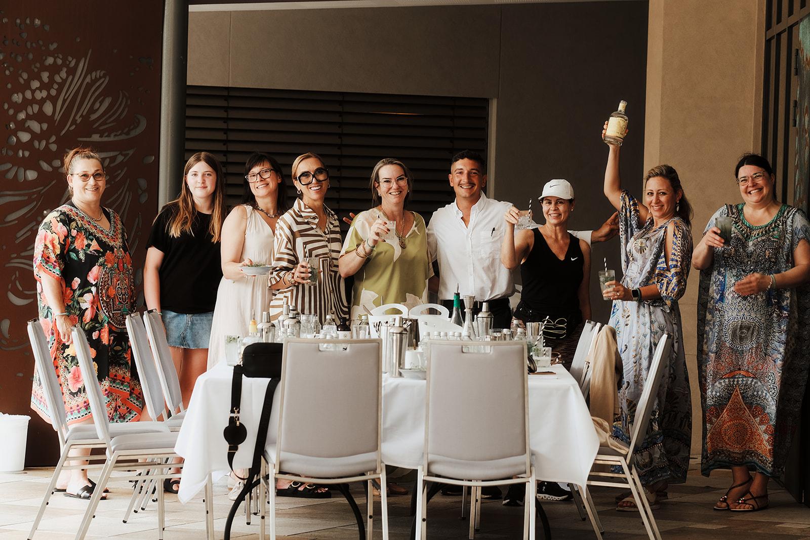 The whole group posed together behind the bar cart, raising their drinks