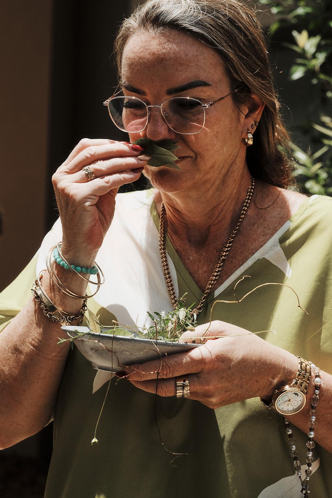 A woman smelling a handful of freshly picked herbs
