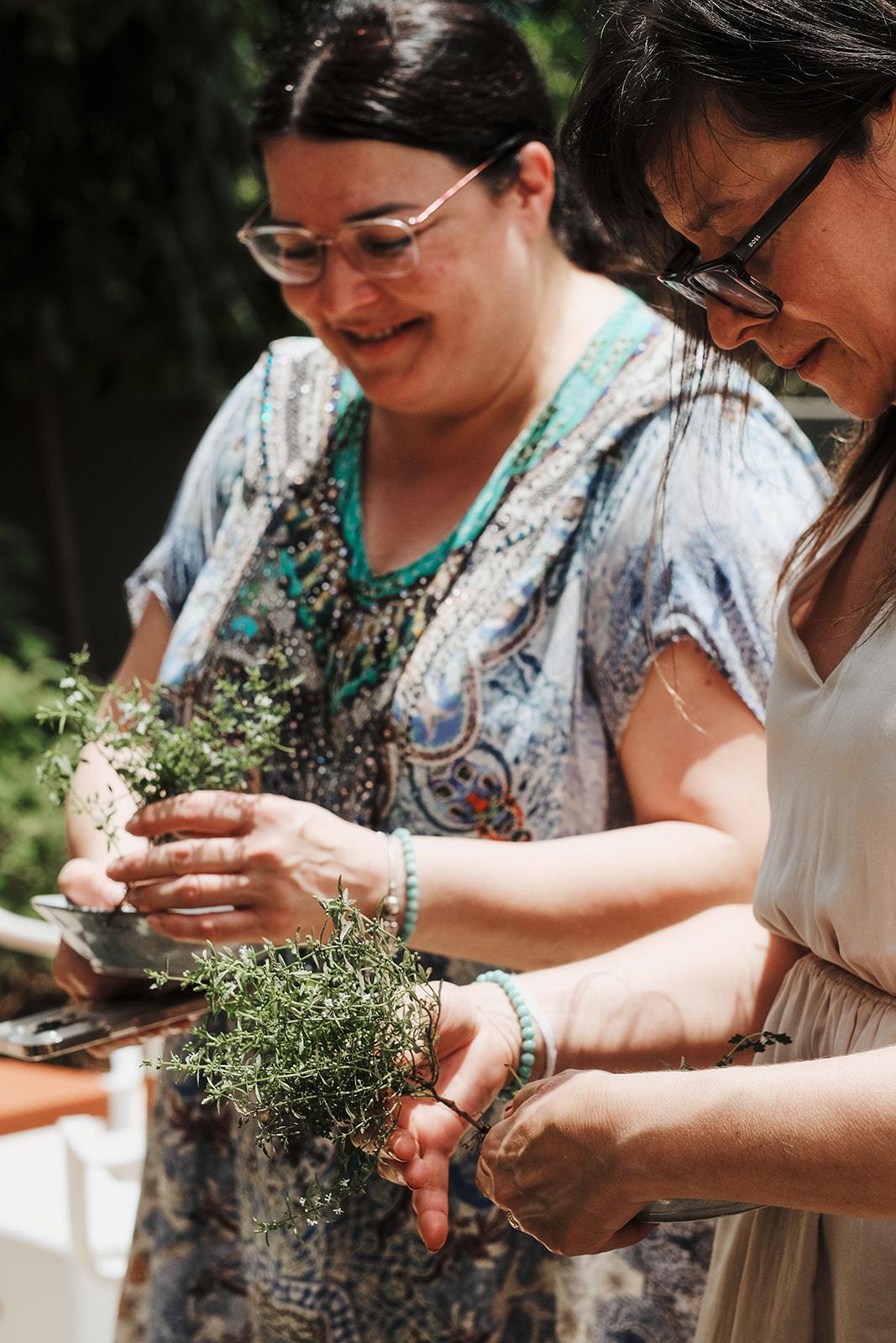 Two women examining a handful of freshly picked herbs together