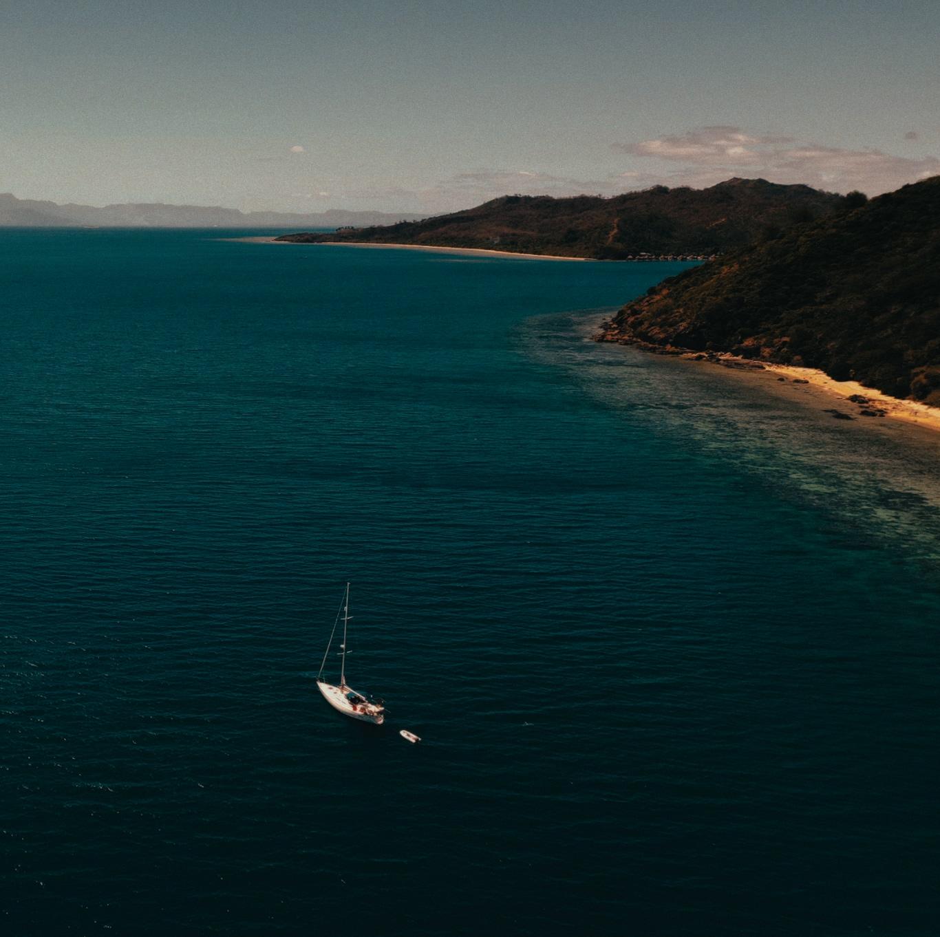 Aerial view of Bella anchored off a turquoise coastline