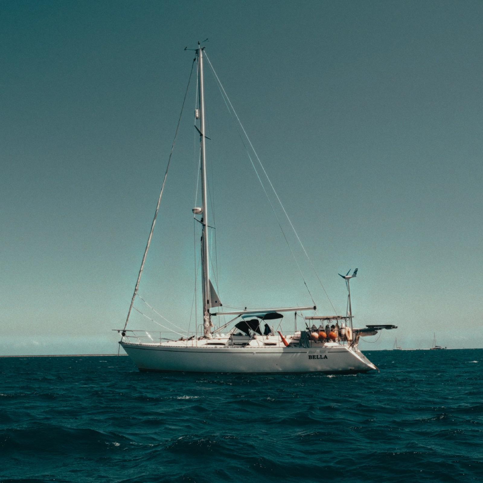 Bella, the family's sailboat, anchored under a clear sky with her name visible on the hull