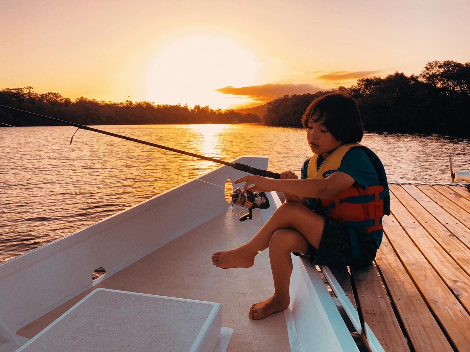 Koa fishing off the bow at sunset, rod in hand