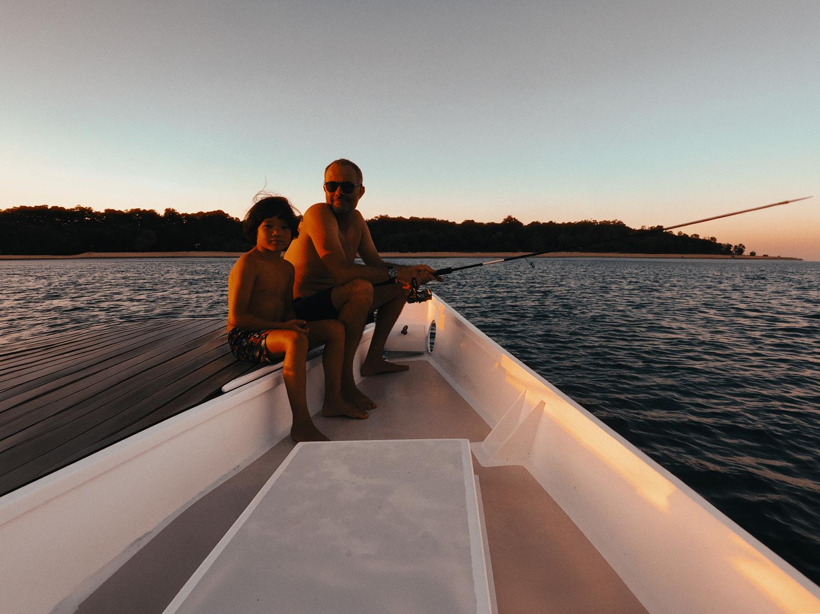 Nharyan and Koa fishing together off the bow at dusk