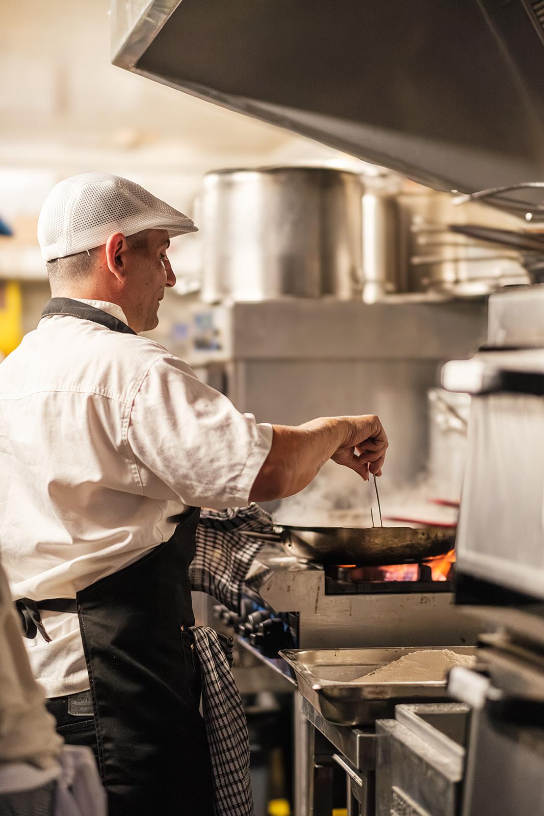 A chef tossing a pan over an open flame in the truck's kitchen