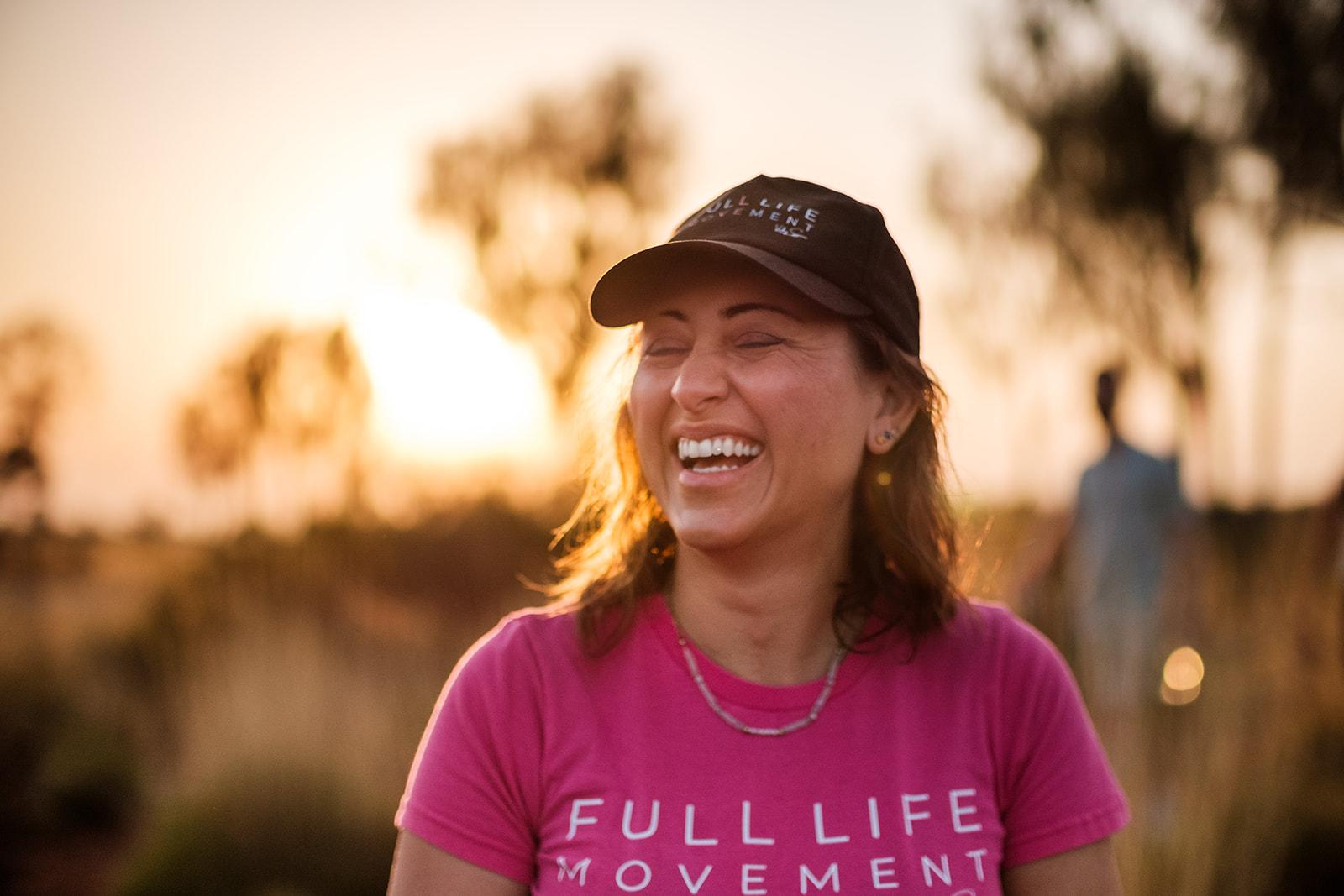 A woman in a Full Life Movement shirt laughing in golden-hour light
