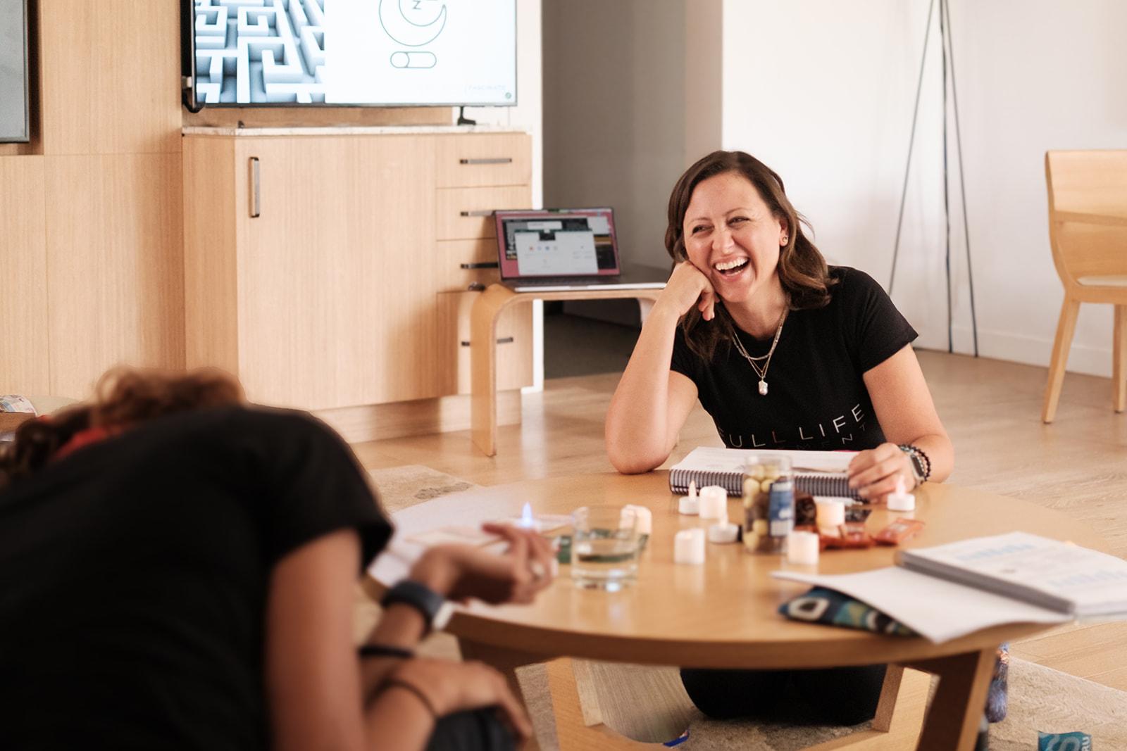 The group laughing together around a table during a workshop session