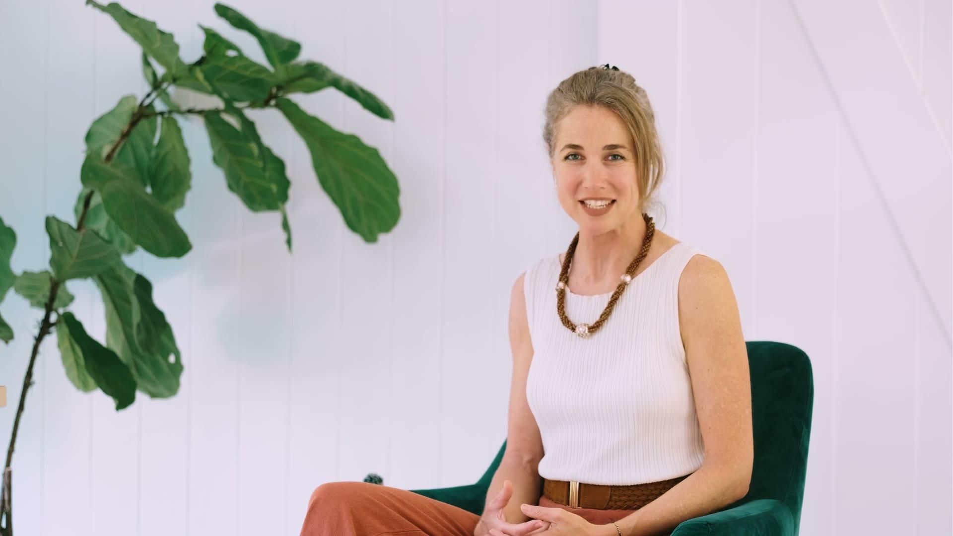 Grace Hawkins presenting to camera in front of a fiddle-leaf fig