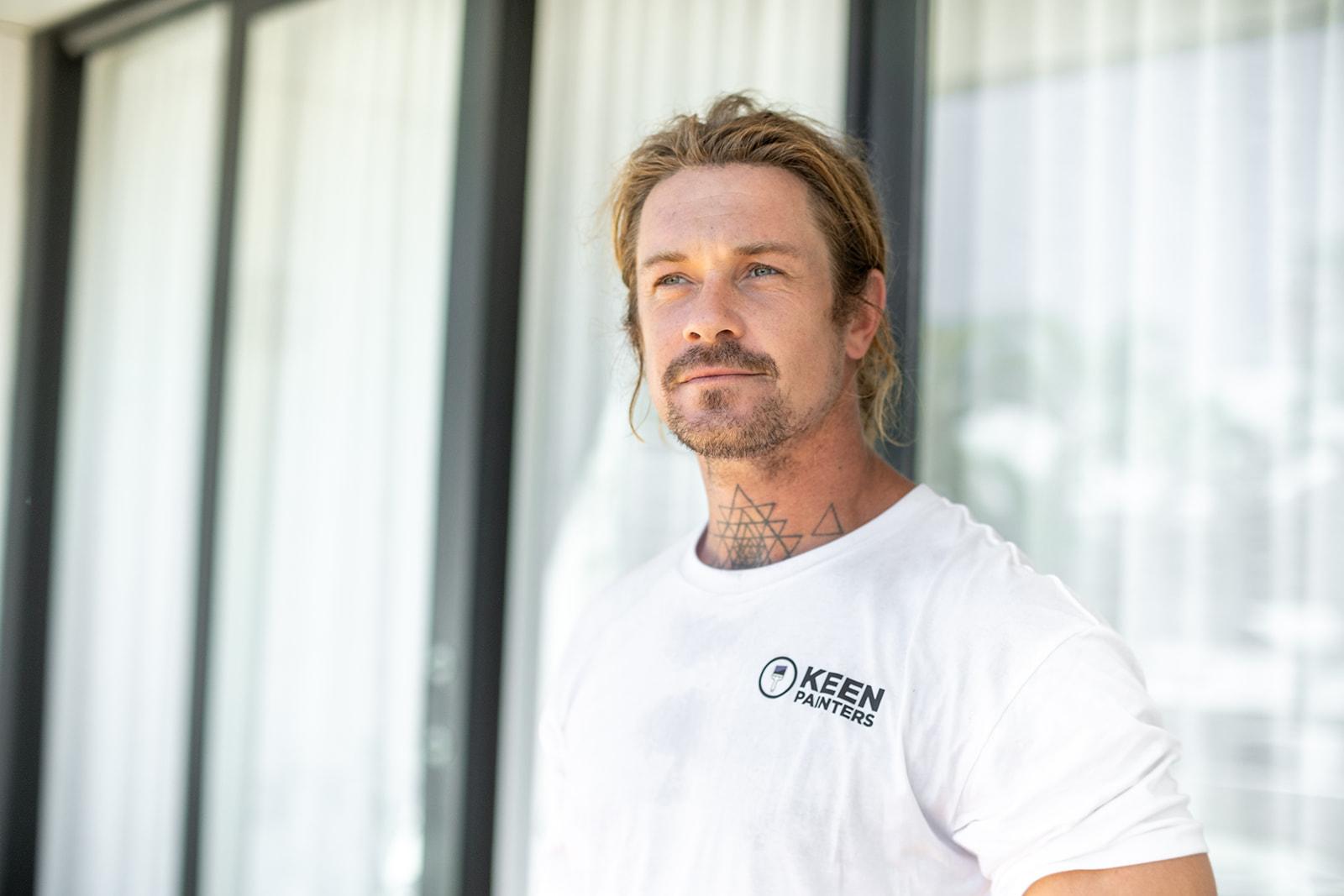 A Keen Painters crew member pausing between sliding glass doors and sheer curtains