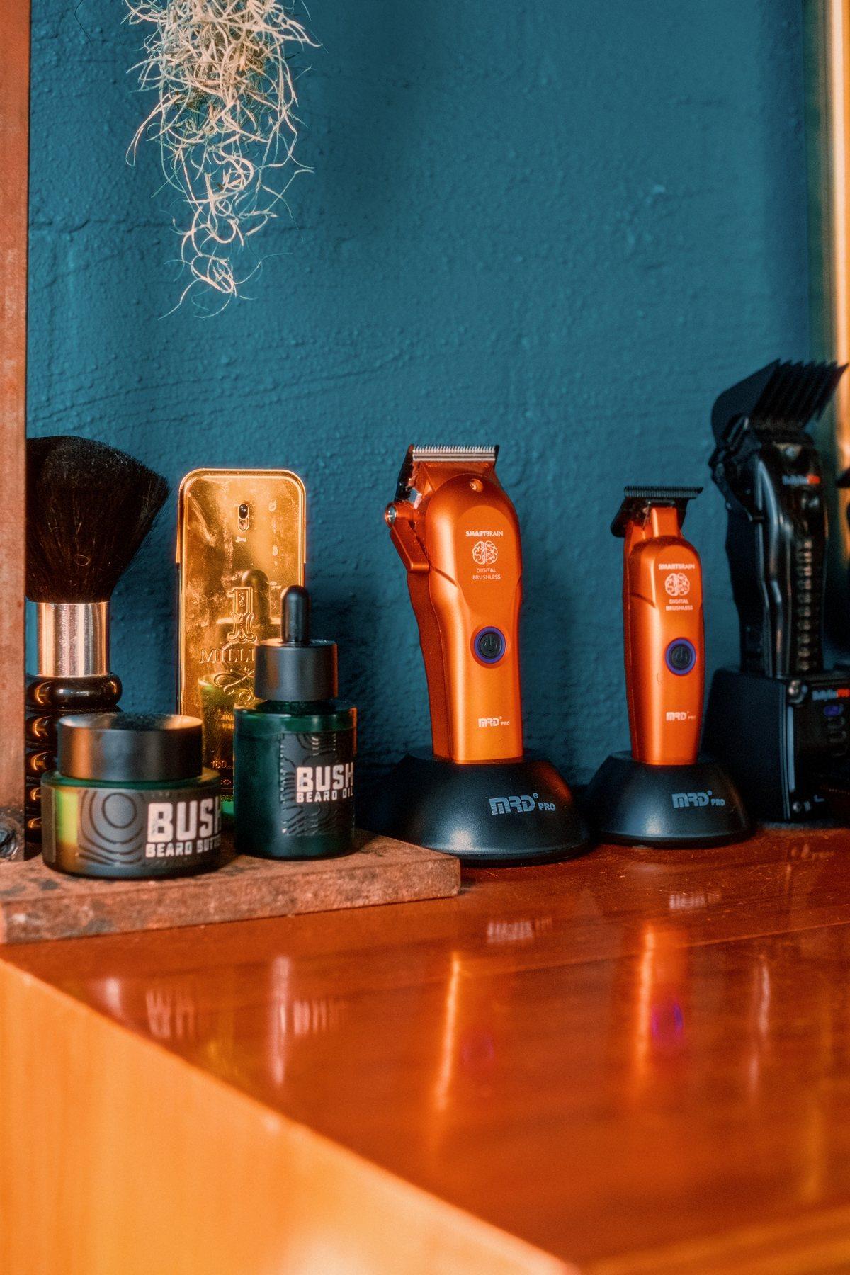 Clippers and beard products lined up on the dresser against a teal wall