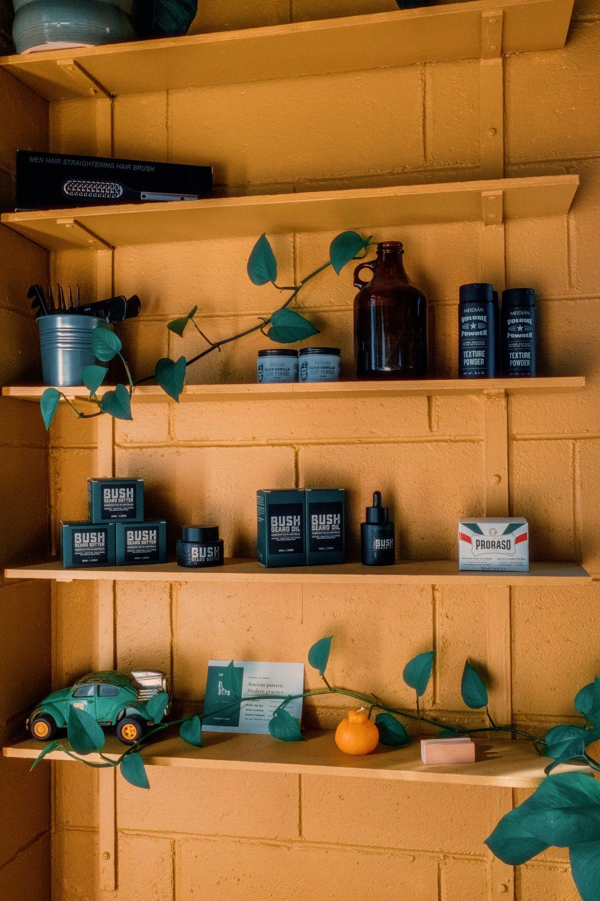 Shelves of beard and hair products against a mustard wall, trailing pothos plant