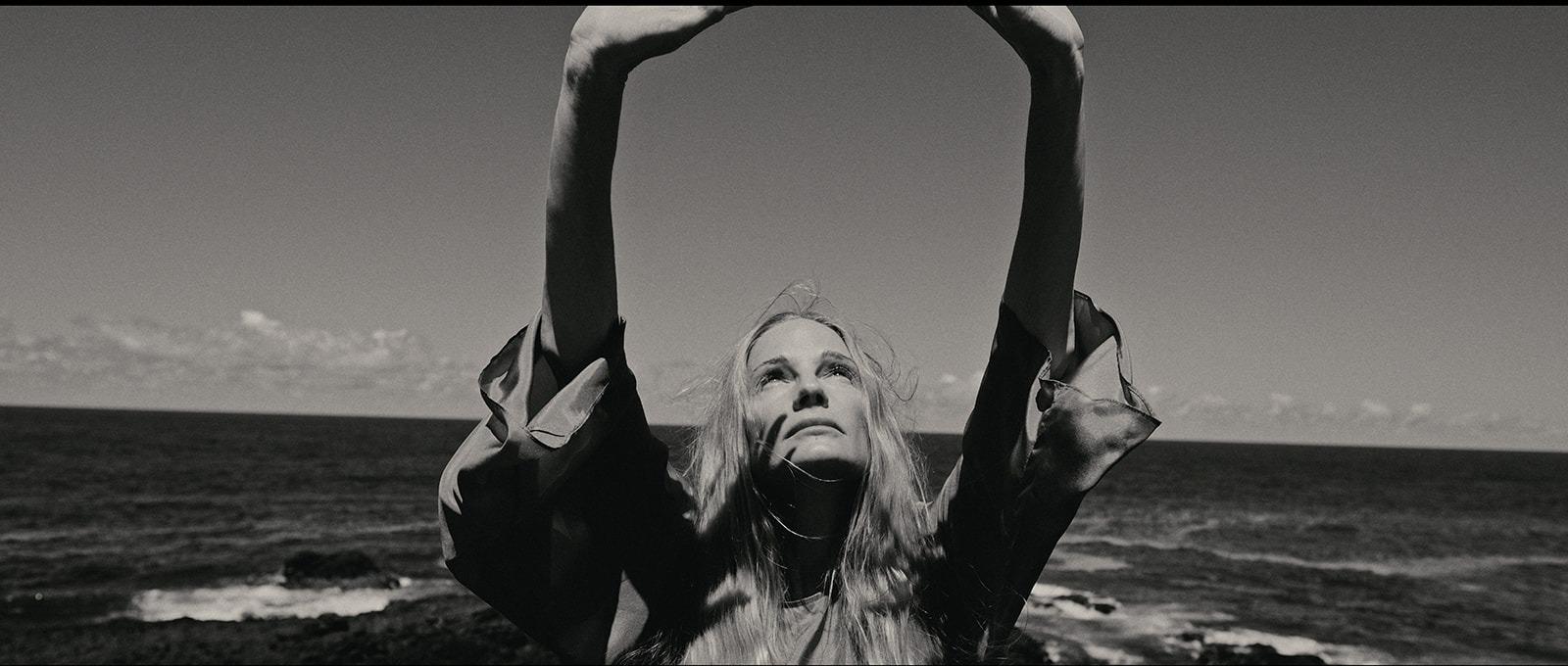 A woman with hands raised together, grainy black and white