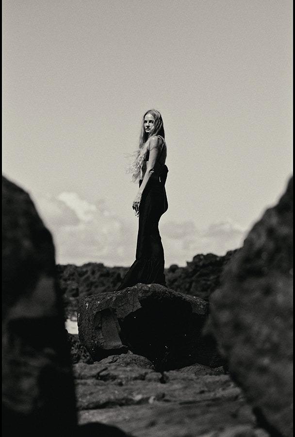 A woman standing on a rock outcrop, black and white