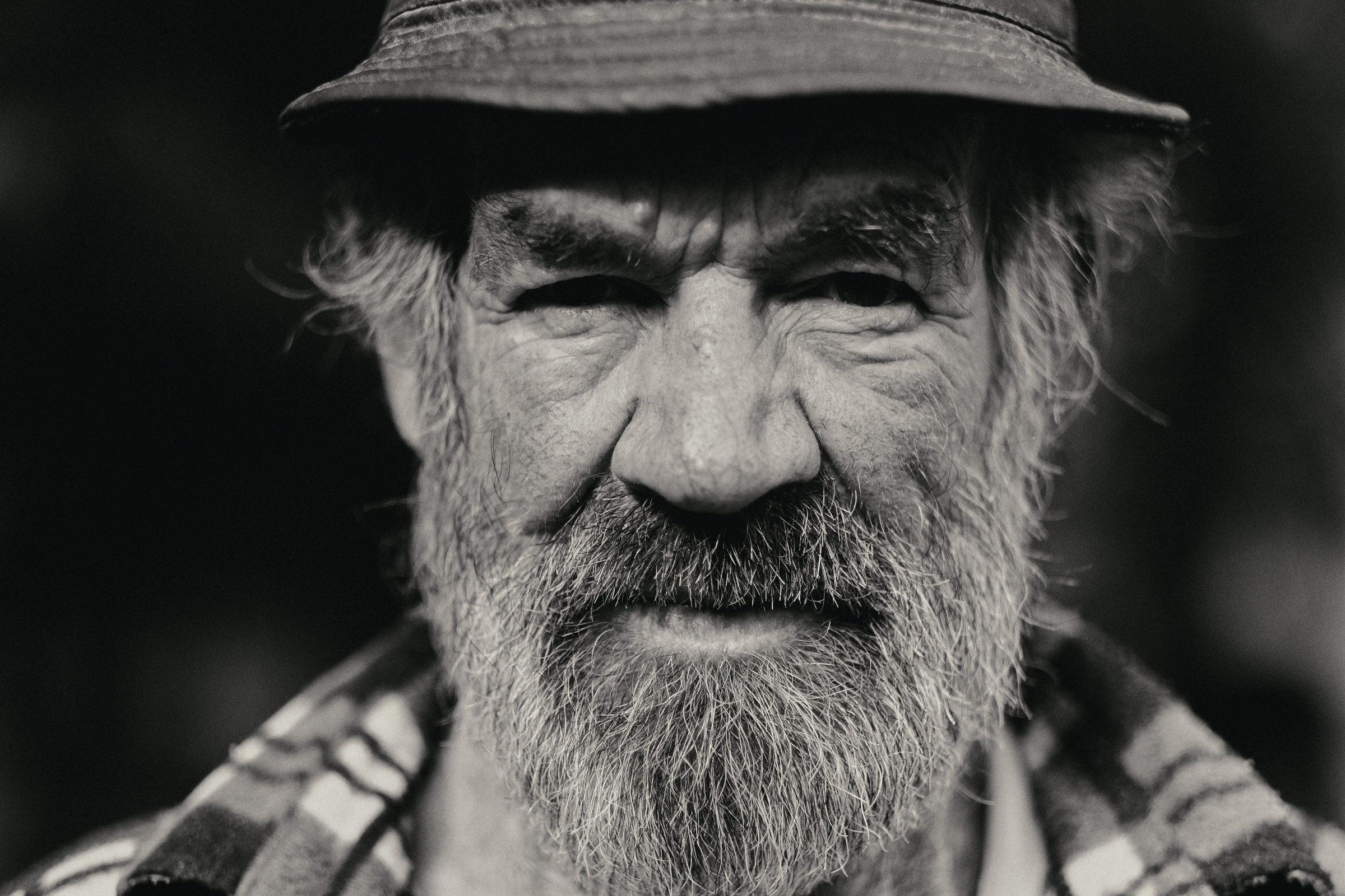 Black and white portrait of an older man with a full beard and a brimmed hat
