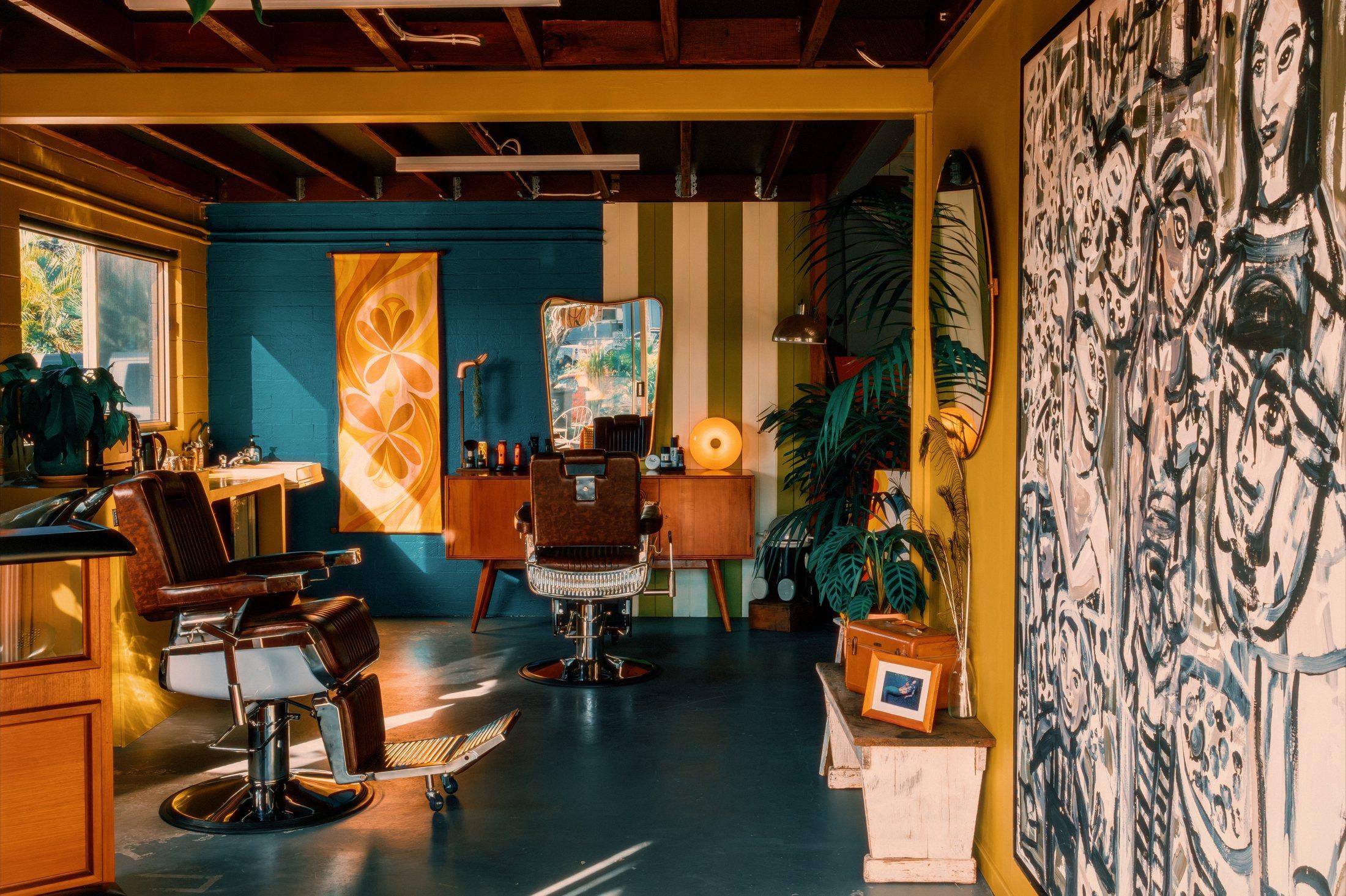Wide shot of the Spunk barbershop interior — teal and mustard walls, vintage barber chairs and a large framed painting
