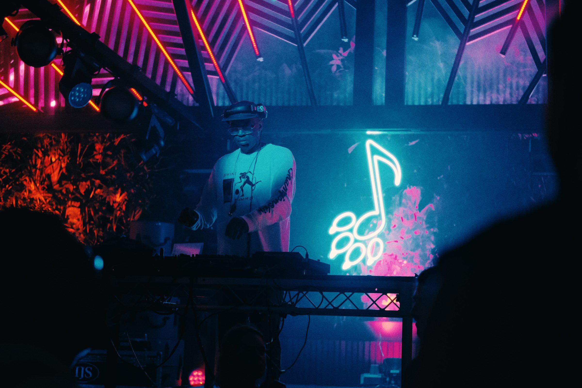 A neon music note glowing blue and pink above a stage at night