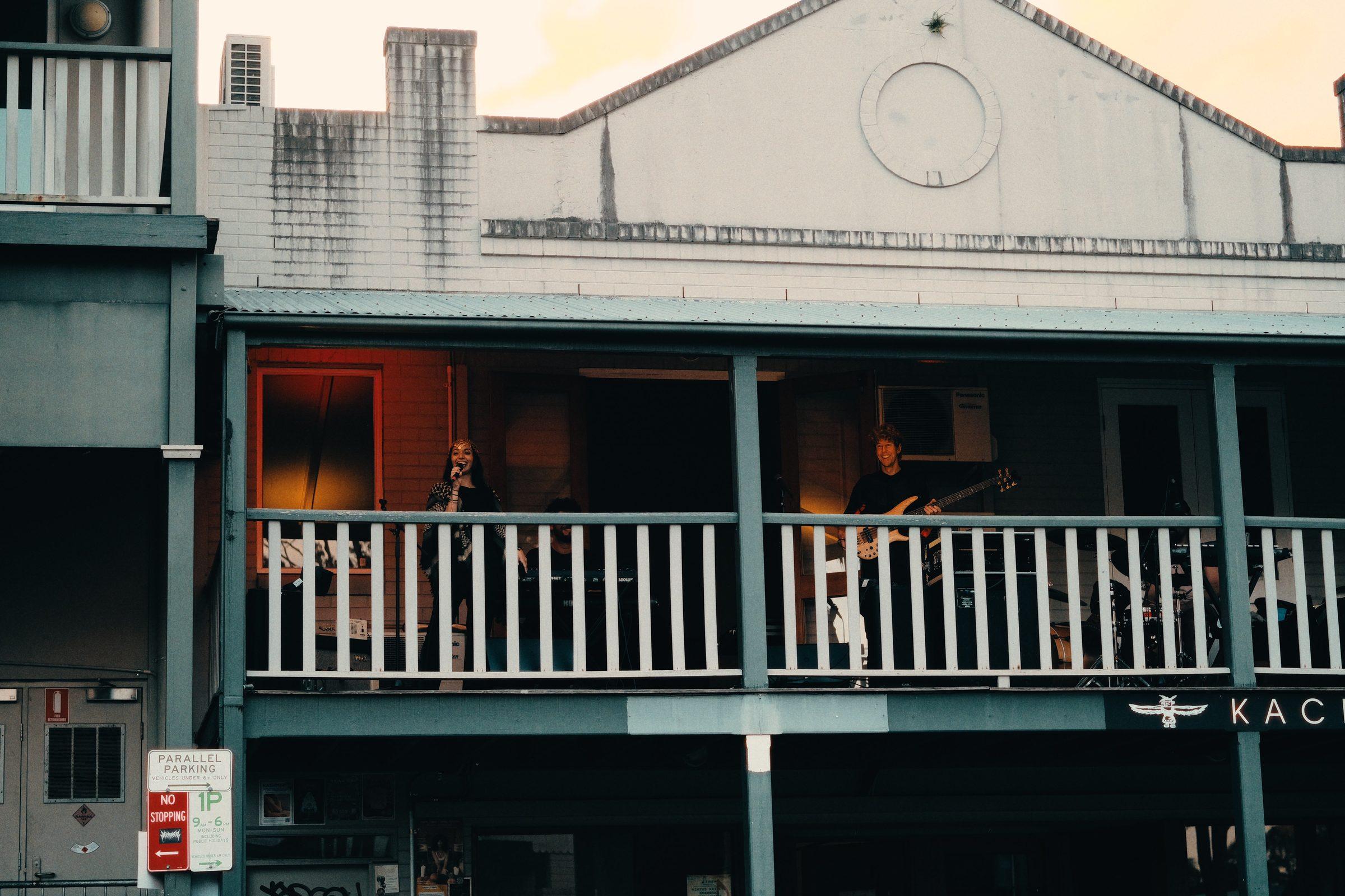 An old weatherboard hotel with a balcony, people on the verandah