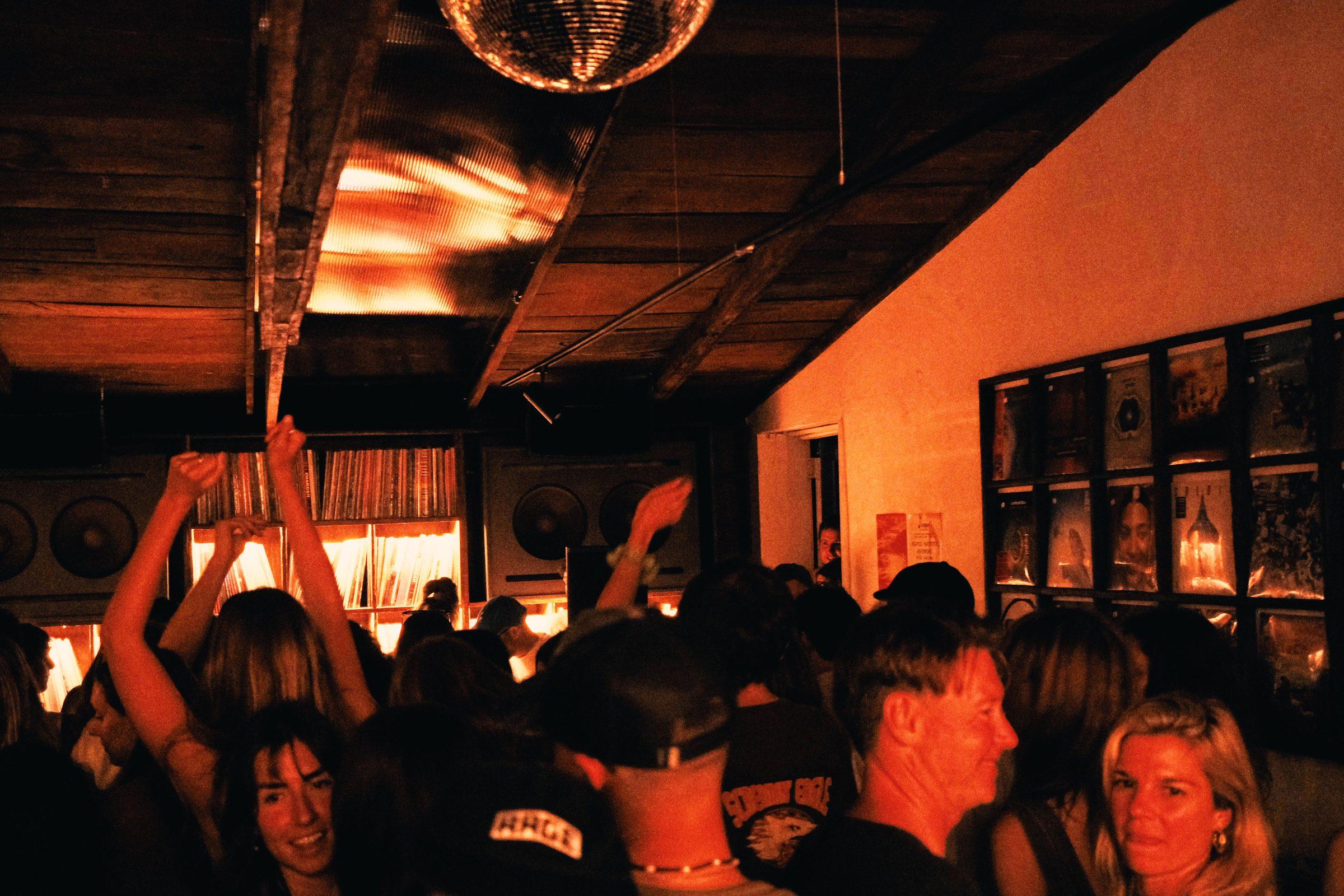 A crowd dancing in a warm-lit room under a mirror ball